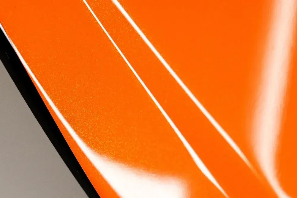 Close-up of vibrant orange surface with angled highlights and a black edge.