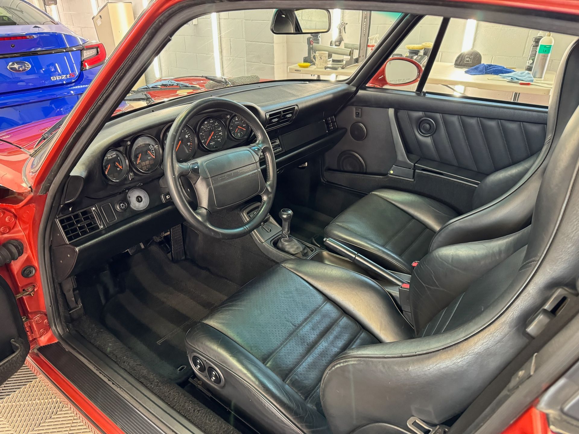 Interior of a red Porsche sports car with black leather seats and dashboard.