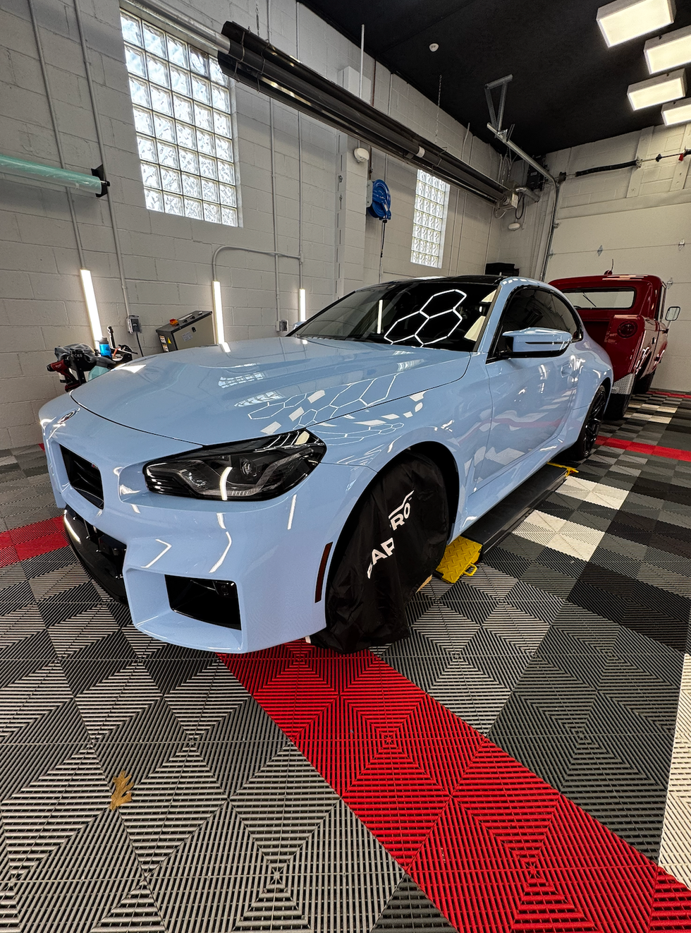 Light blue car in a car wash bay, with black accents.