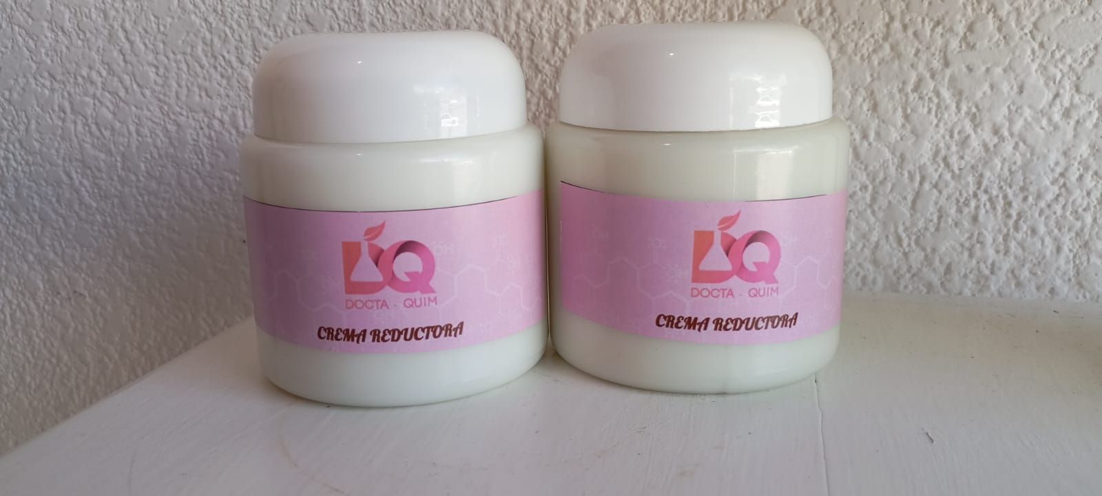 Envase blanco con etiqueta rosa, texto