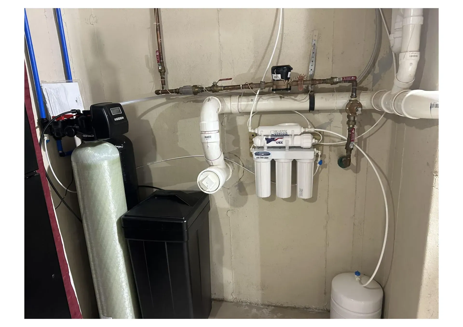 Water filtration system in a basement. Includes tanks, pipes, and control panels.