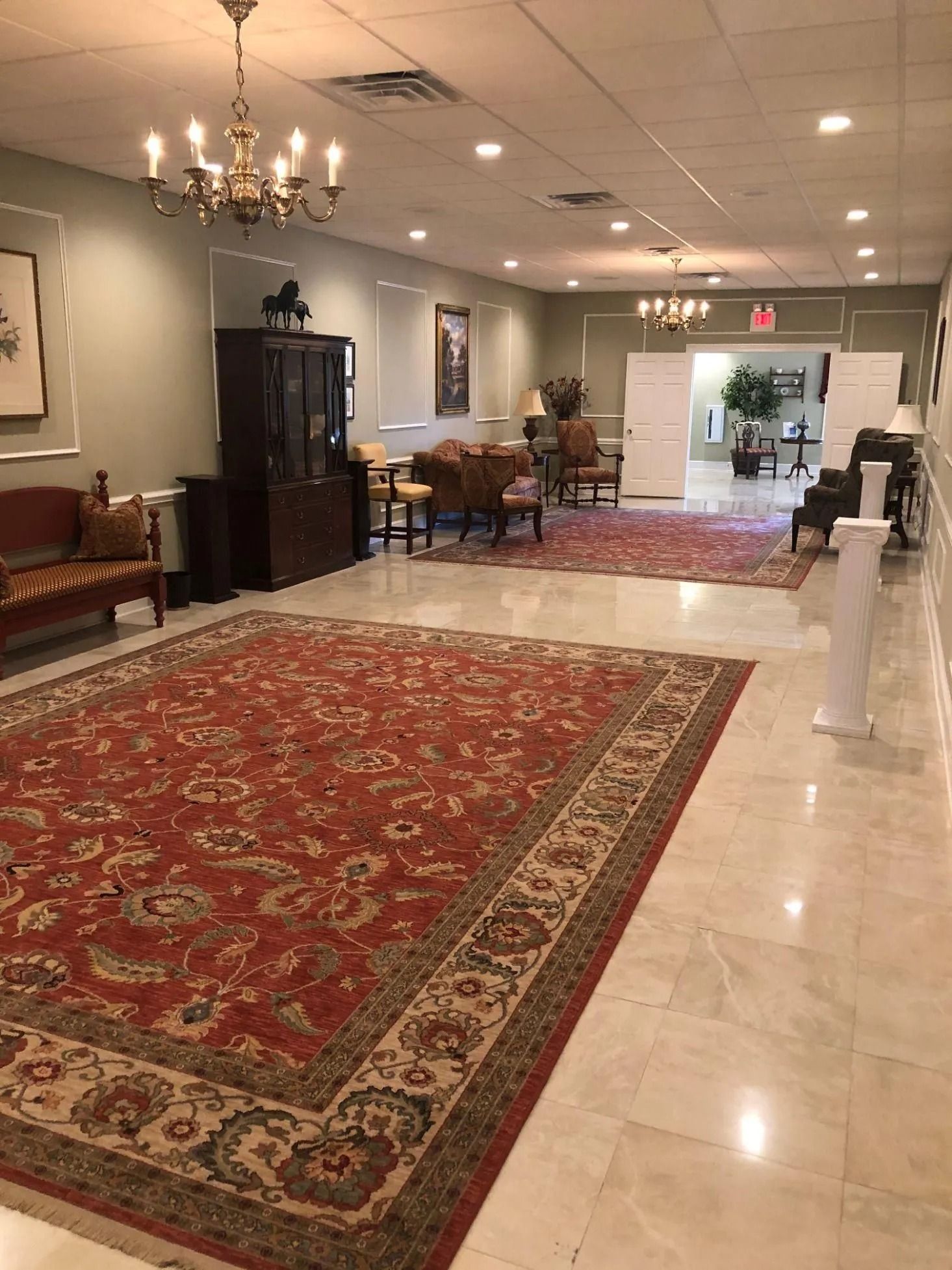 Hallway with red rug, furniture, and chandeliers.