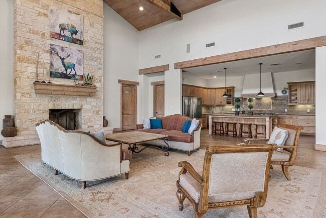 Clubhouse with fireplace, couches, and open kitchen, neutral colors, stone and wood accents.