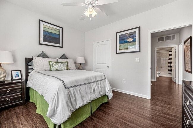 Bedroom with bed, nightstands, art, door to hallway, and ceiling fan.