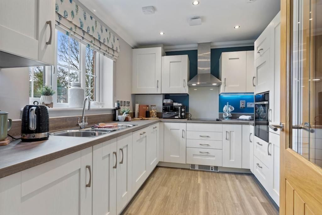 A kitchen with white cabinets and a wooden floor