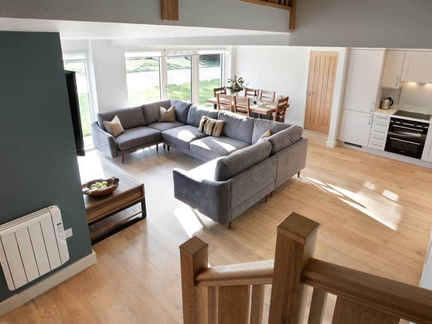 A living room with a large sectional couch and a kitchen