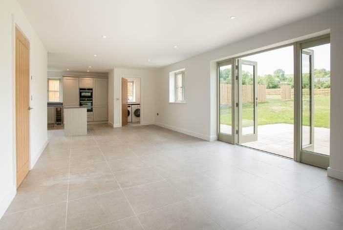 Brailes, An empty living room with sliding glass doors and a kitchen.