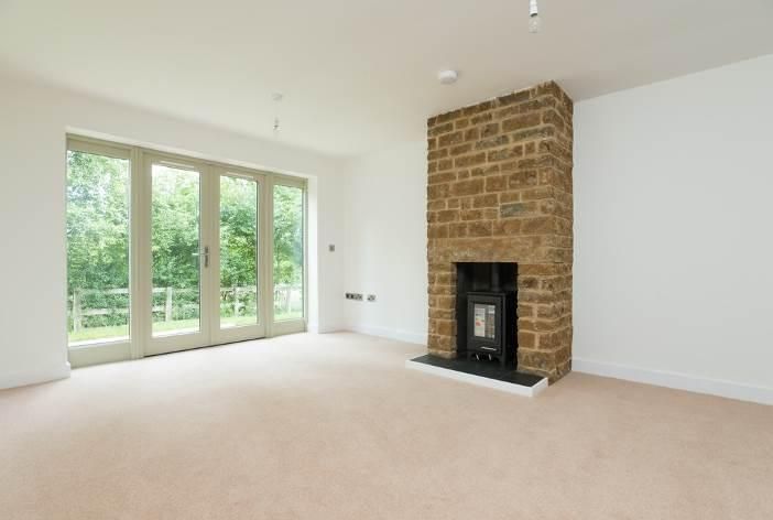 Brailes, An empty living room with a fireplace and sliding glass doors.