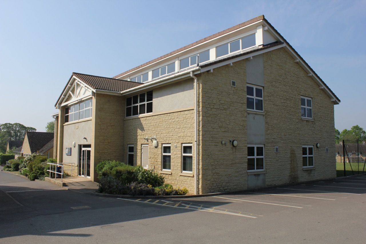 A large brick building with a lot of windows and a parking lot in front of it.