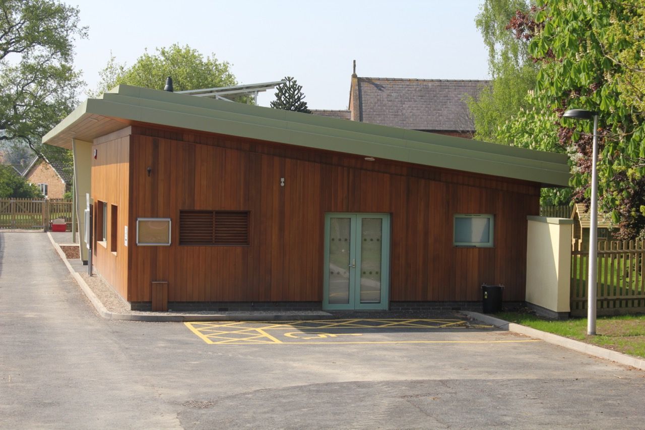 A small wooden building with a green roof