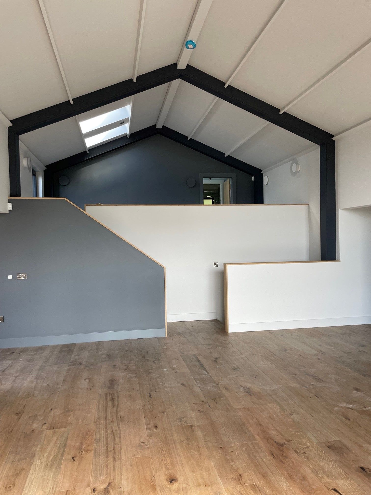 An empty room with a wooden floor and a staircase leading to the second floor.