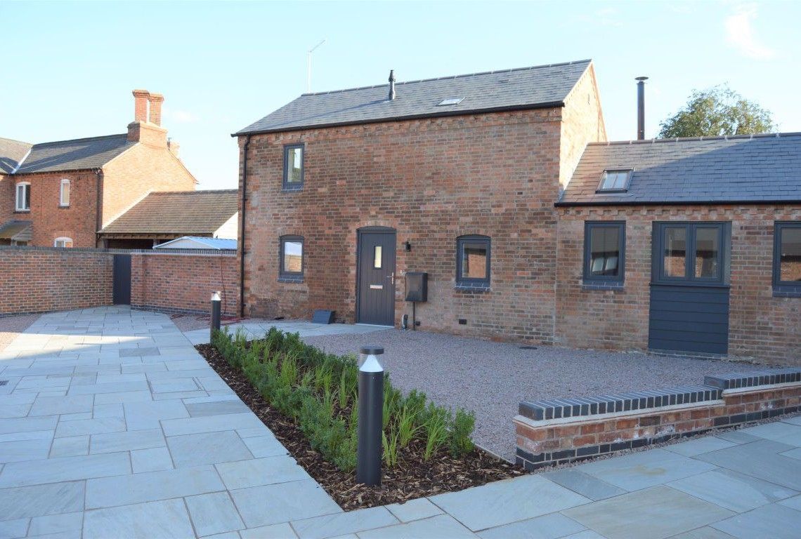 Newbold Farm,  A brick house with a slate roof and a brick driveway in front of it.