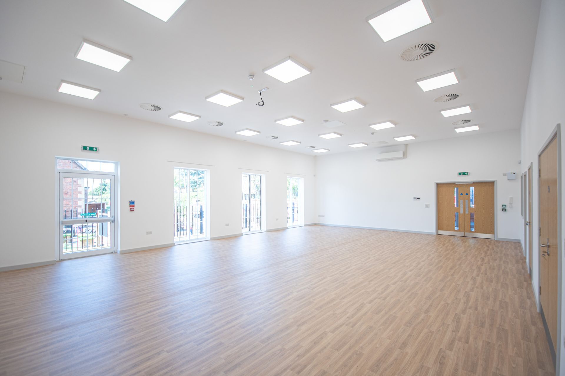 Old School Community Room, A large empty room with wooden floors and white walls.