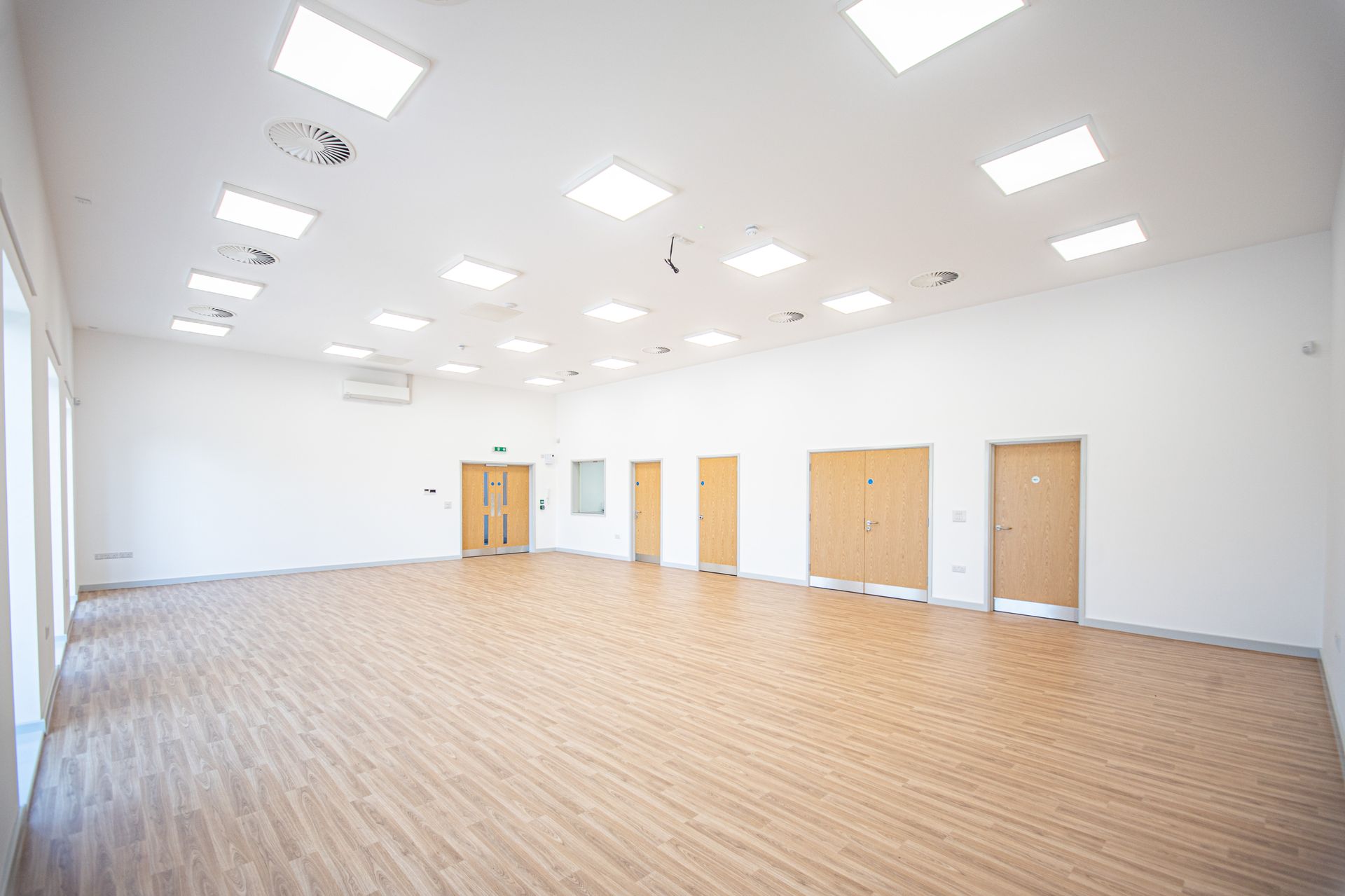 Old School Community Room, A large empty room with wooden floors and white walls.