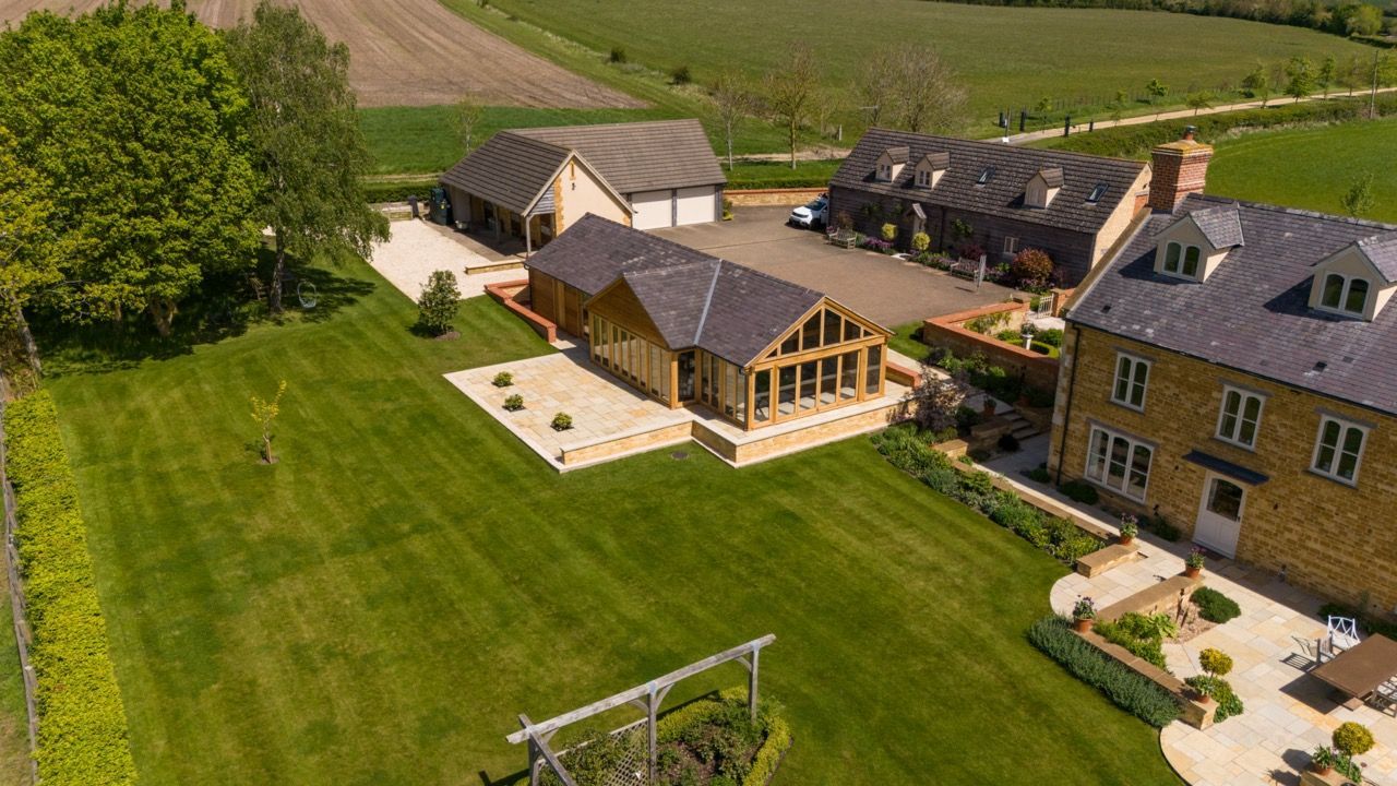 St Dennis Pool House, An aerial view of a large house in the middle of a lush green field.