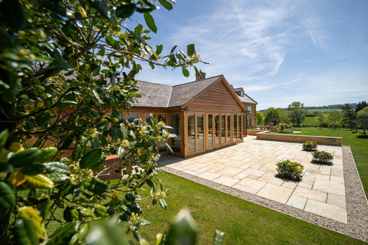 St Dennis Pool House, A large wooden house with a large patio in front of it.