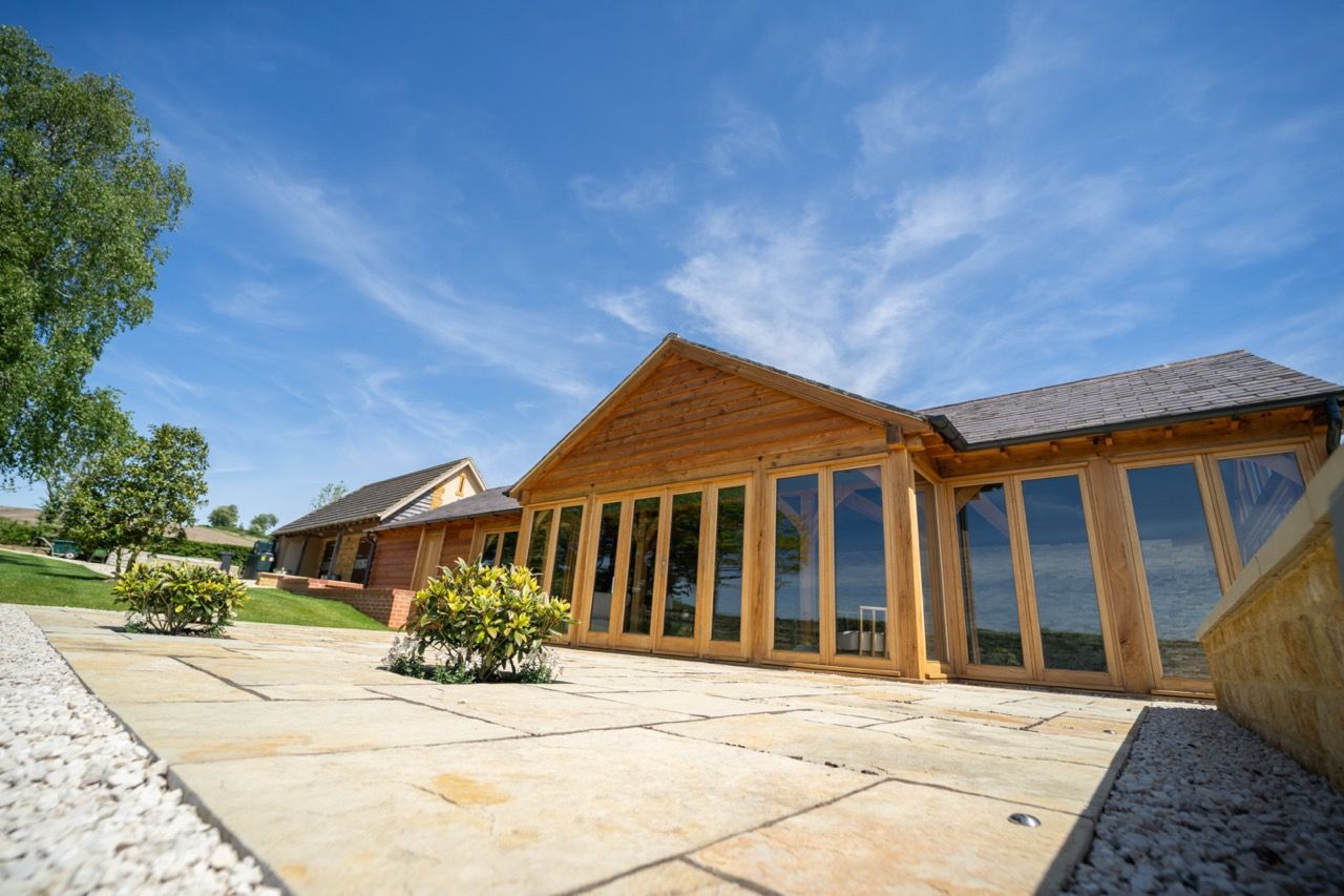 St Dennis Pool House, A large wooden house with a lot of windows on a sunny day.