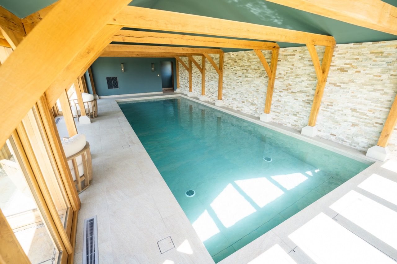 St Dennis Pool House, A large indoor swimming pool with wooden beams and a stone wall