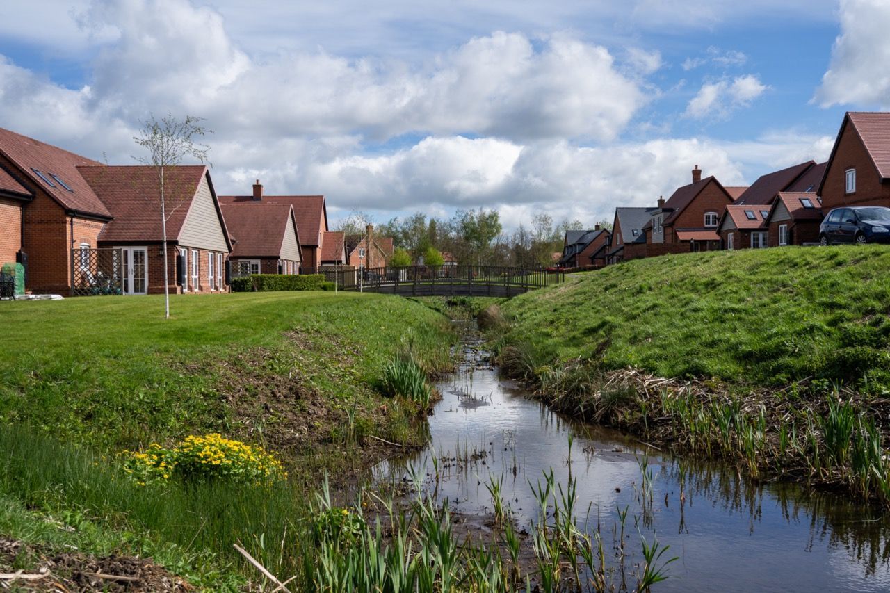 Limetree Village, a stream running through a residential area with houses in the background.