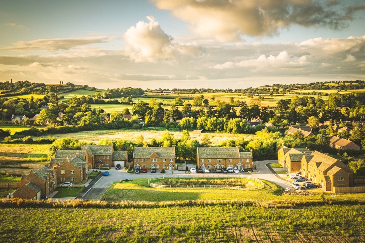 Warmington Fields, an aerial view of a residential area surrounded by fields and trees.
