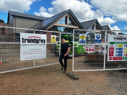 A man is walking through a fence with a sign that says trendgrey on it.