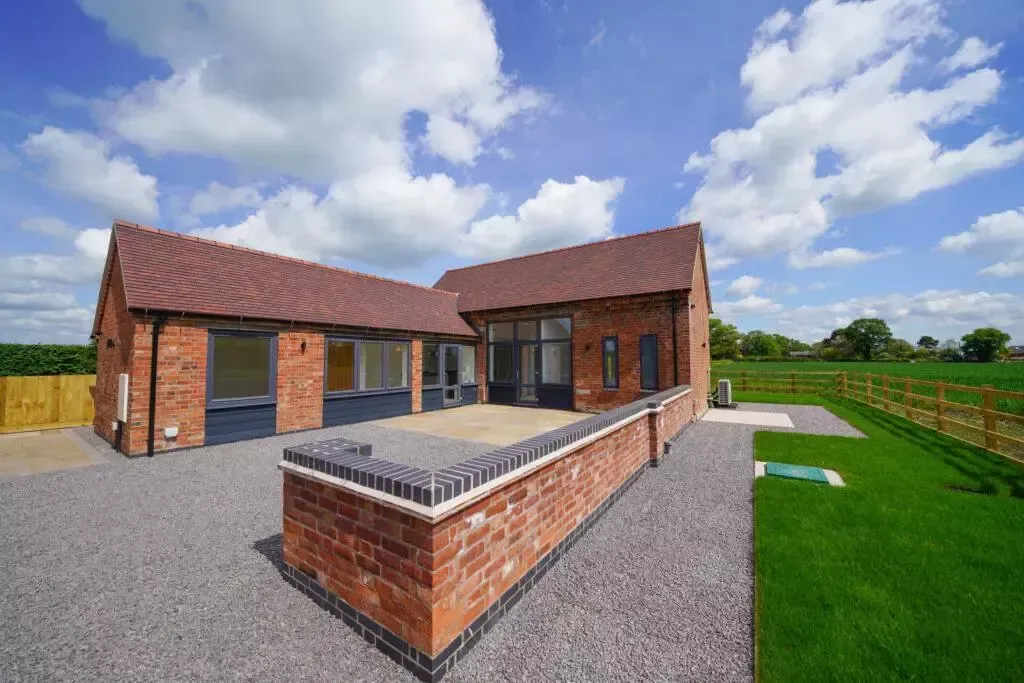 A large brick house with a large lawn in front of it.