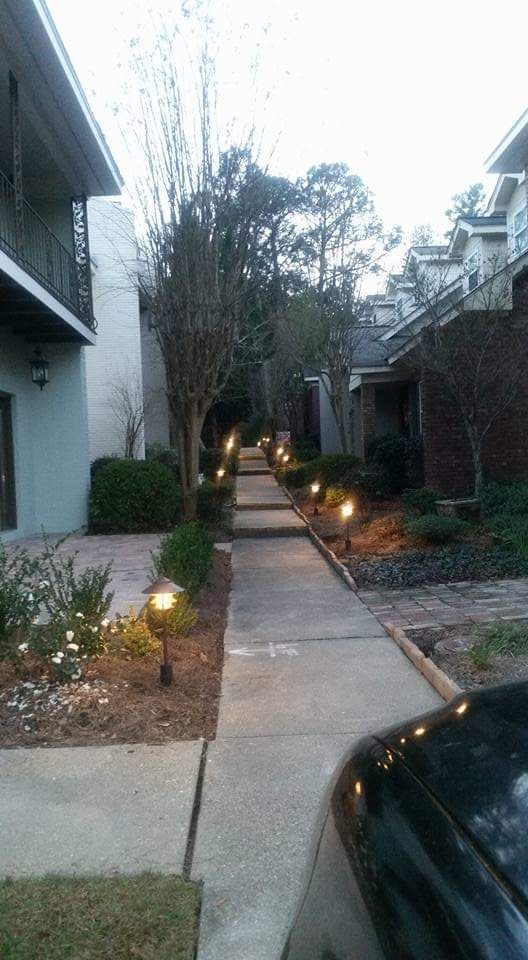 A sidewalk leading to a building with a car parked on the side of it.