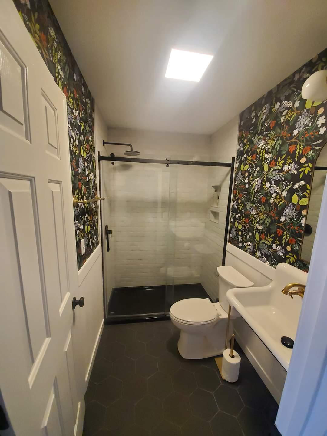 A bathroom with a toilet , sink and shower.