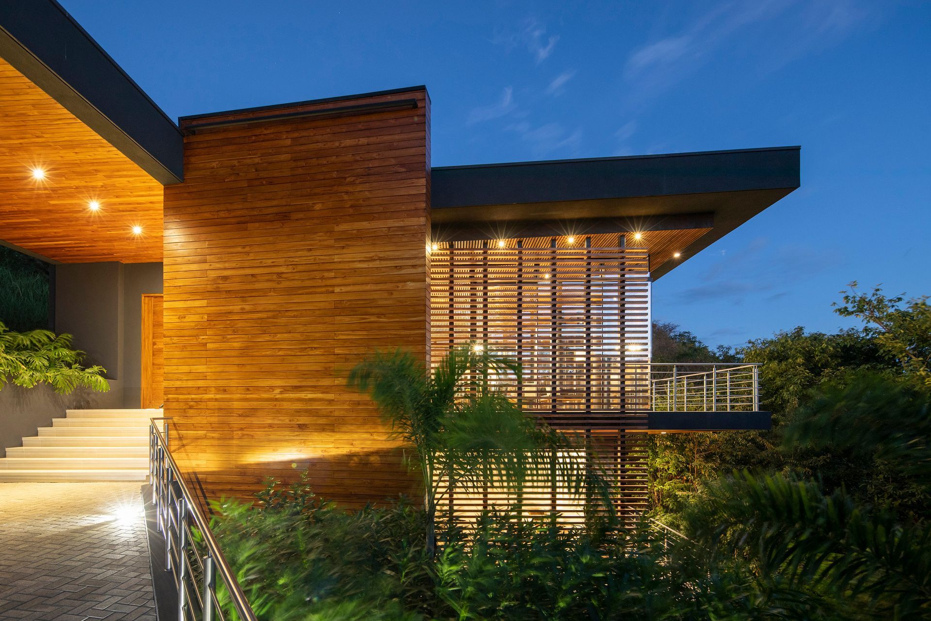 A modern house with a wooden facade is lit up at night. 