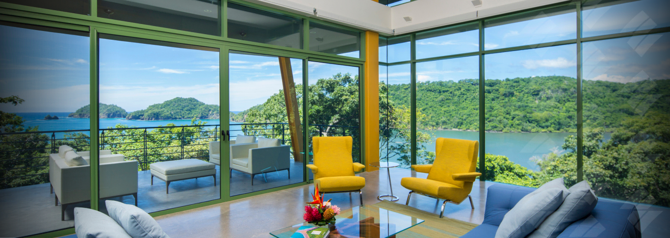 a living room with a blue couch and yellow chairs and a view of the ocean .
