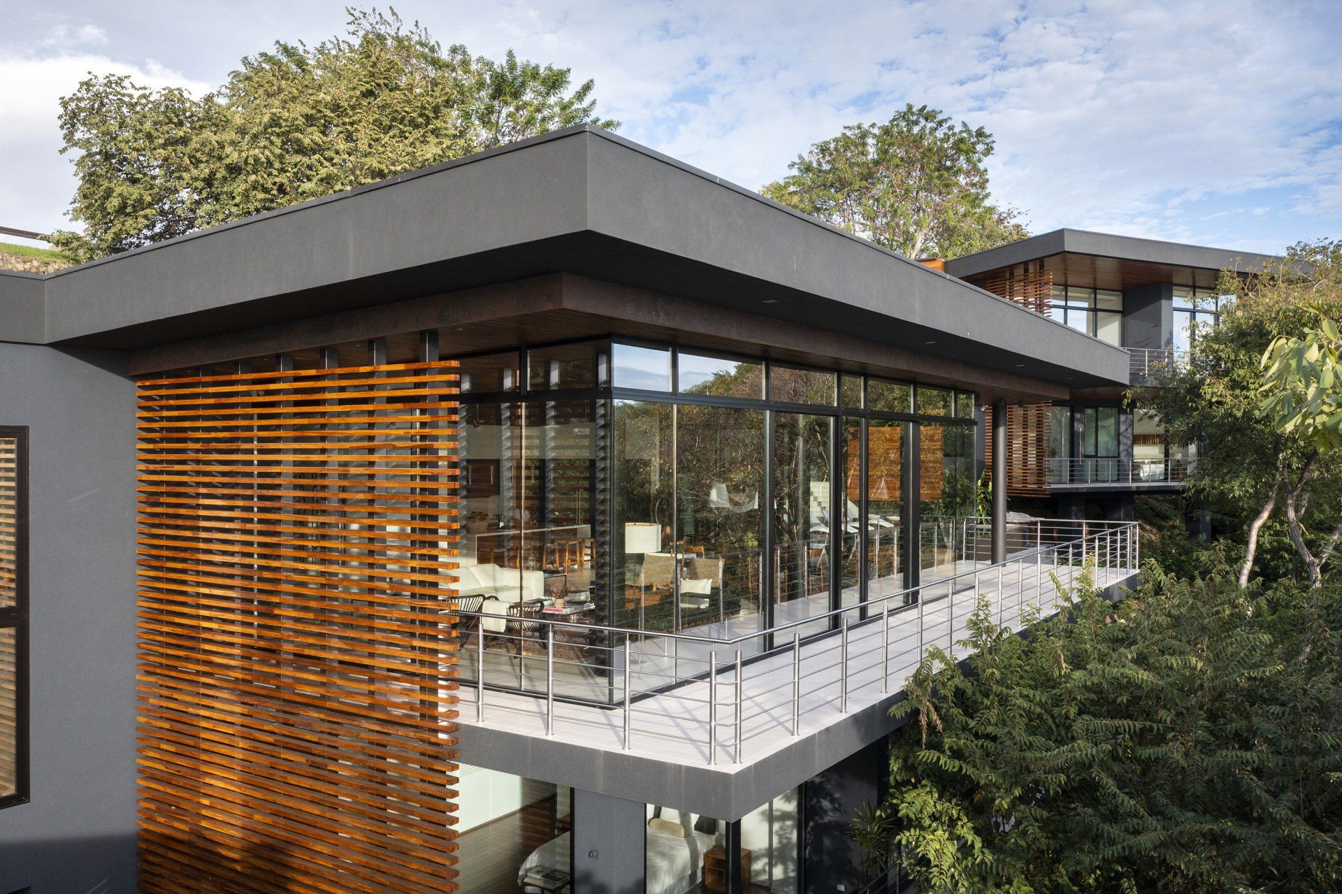 Exterior of large tropical modern luxury home with lounge chairs and a pool