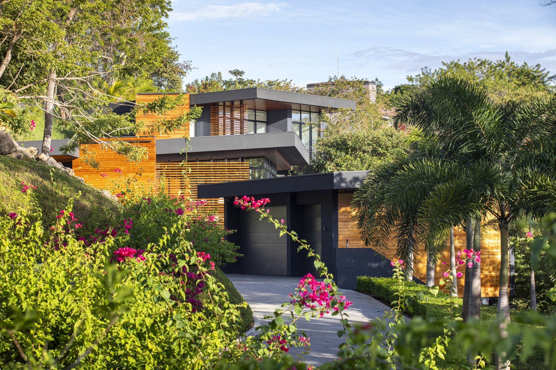 a modern house is surrounded by trees and flowers .