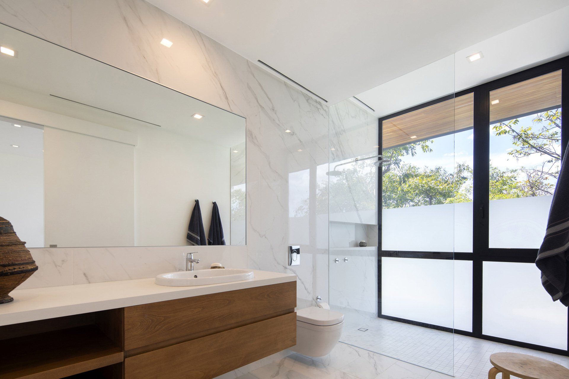 a bathroom with a sink , toilet , and large window .- casa aramara by sarco