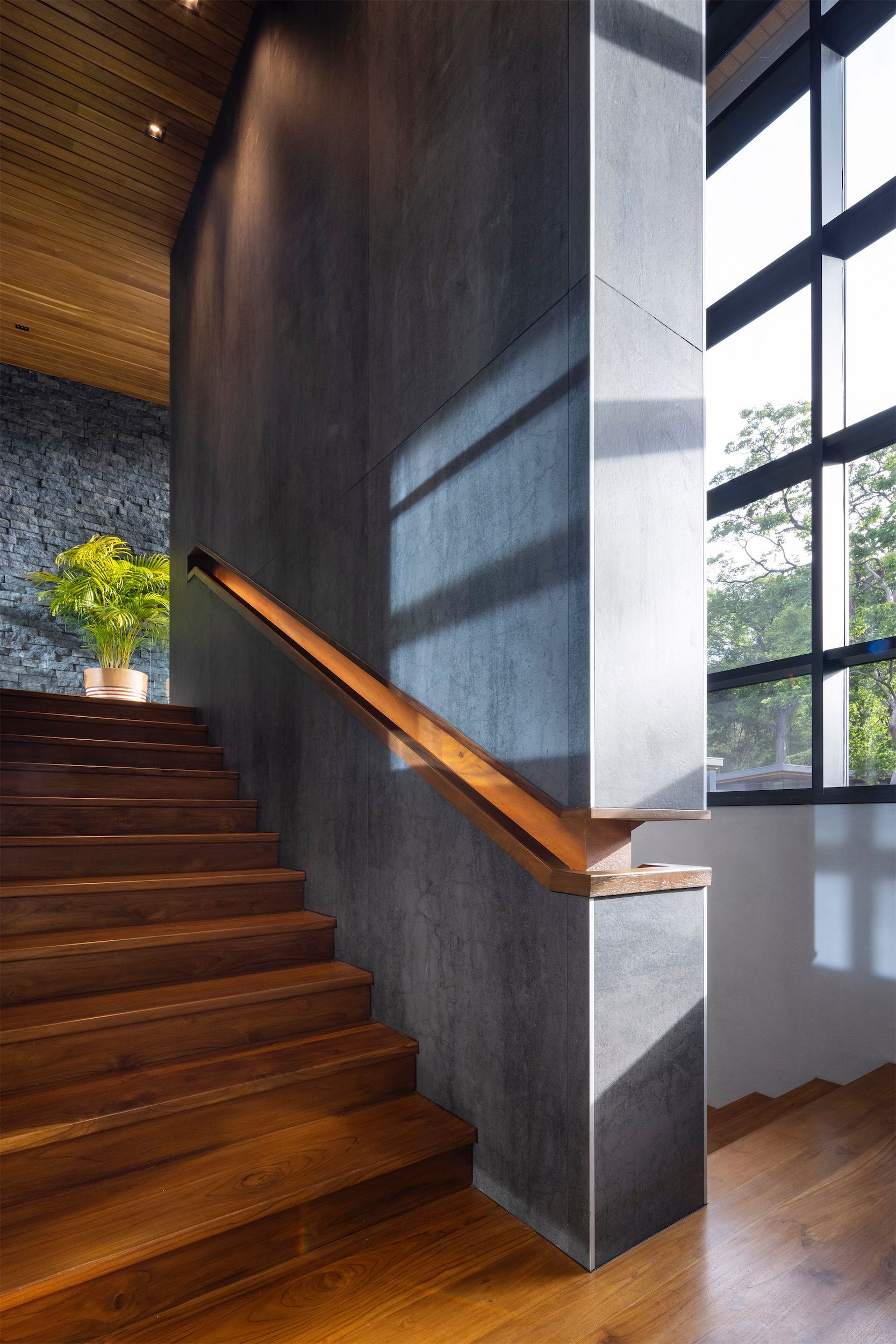 a staircase with a wooden railing and a concrete wall .