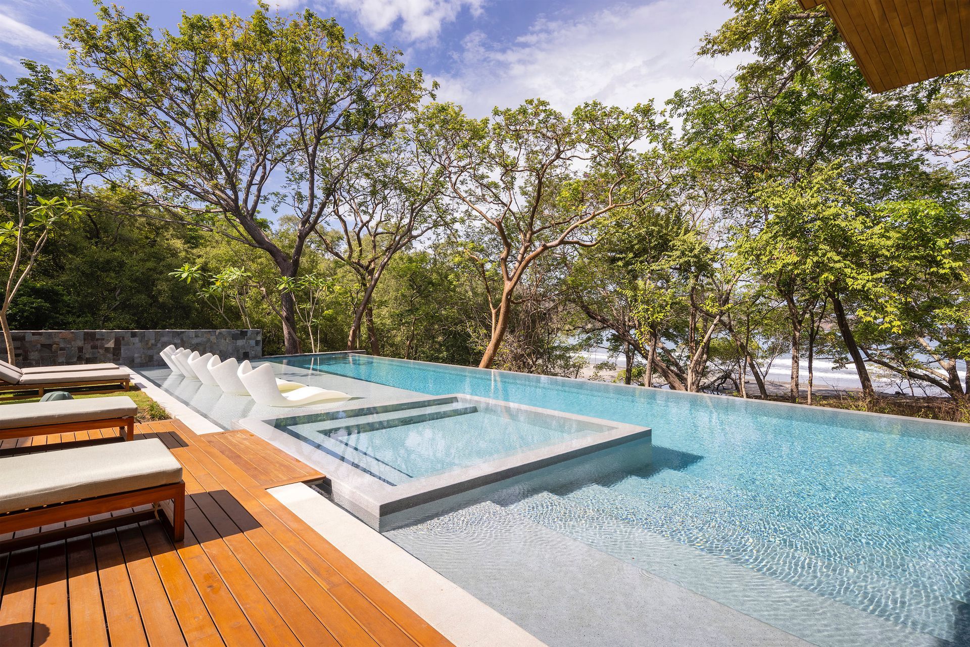 a large swimming pool surrounded by trees and a wooden deck .