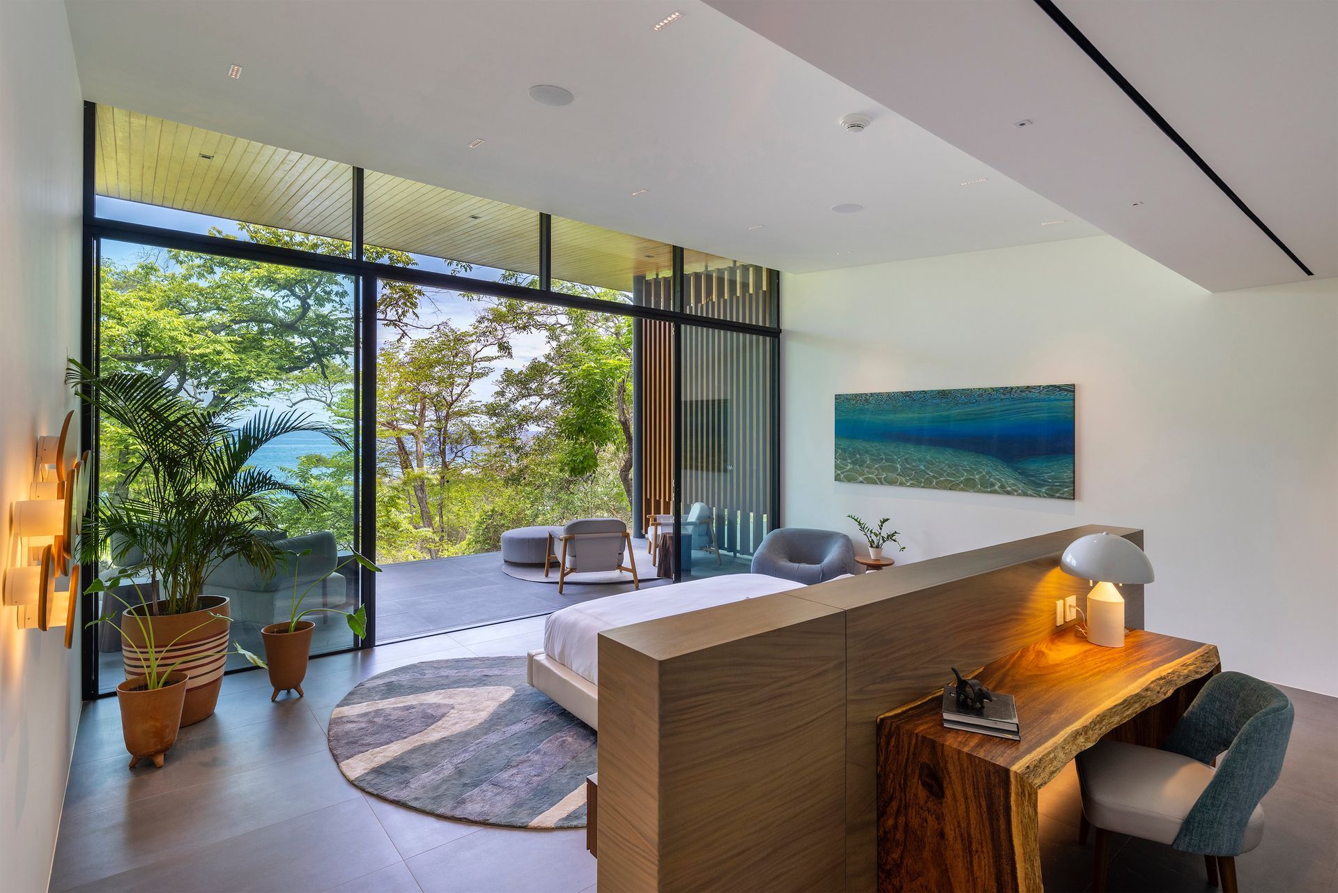 a bedroom with a large bed , desk , chairs and a large window .