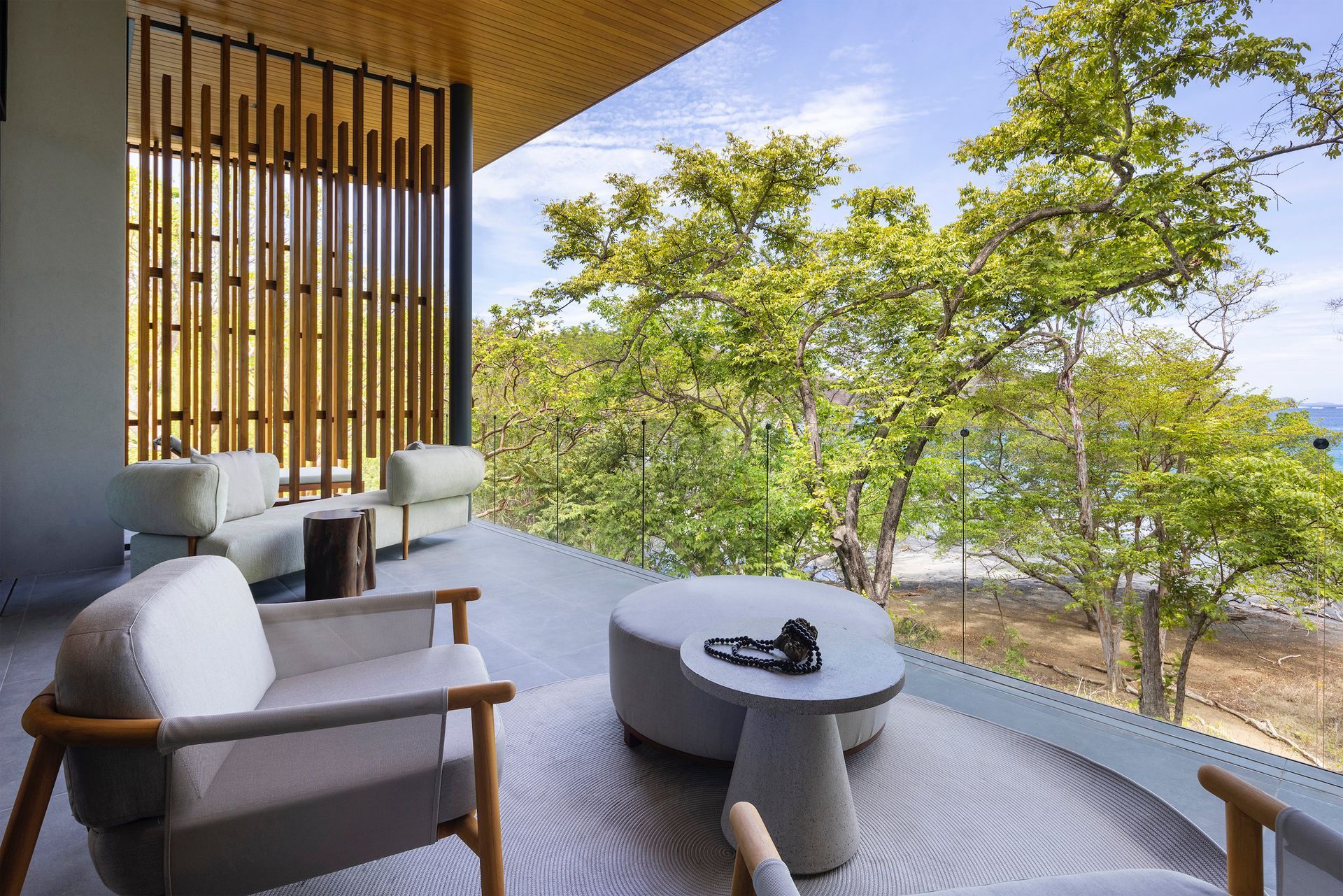 a balcony with chairs , a table and a view of the ocean .