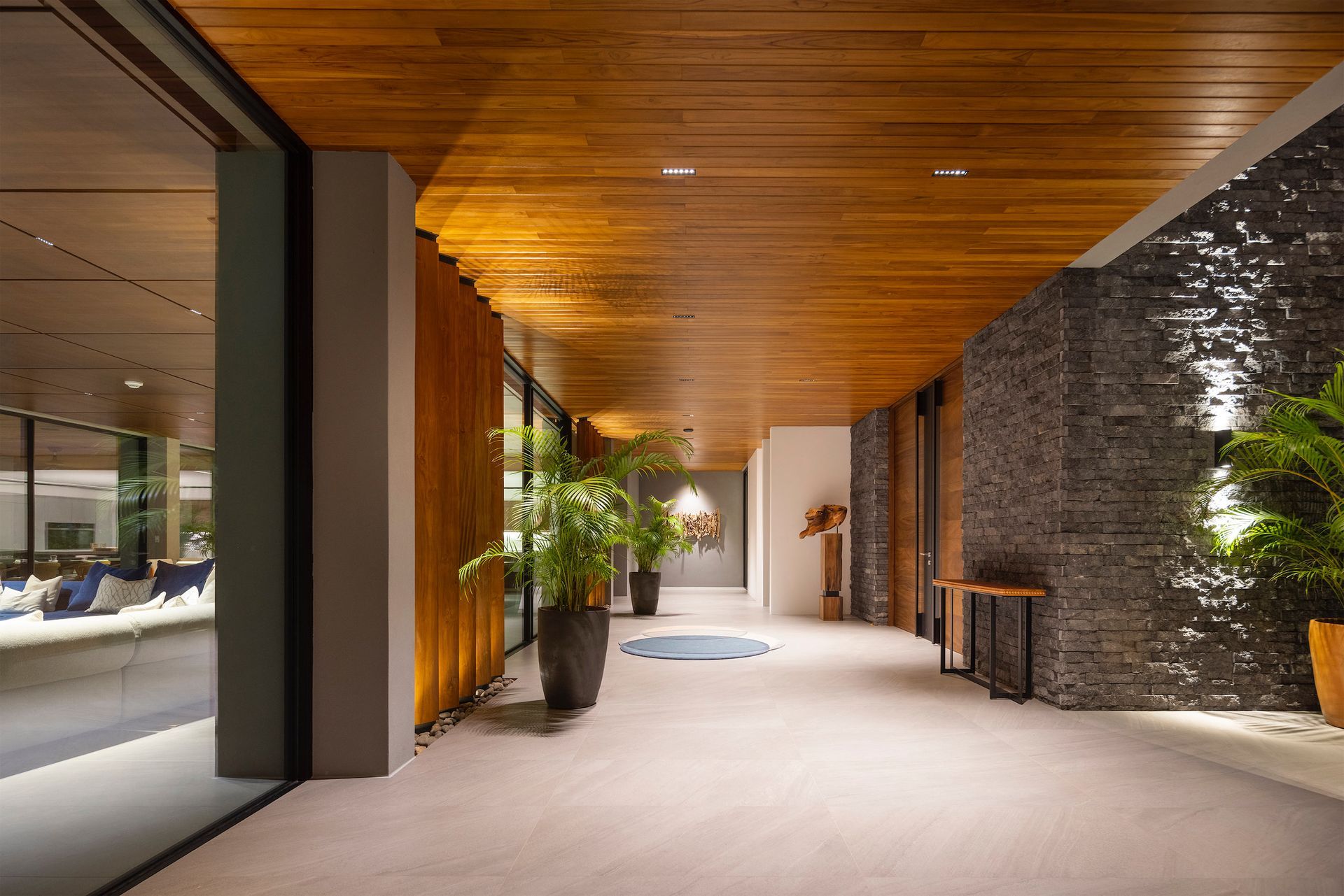 a long hallway with a wooden ceiling and potted plants .