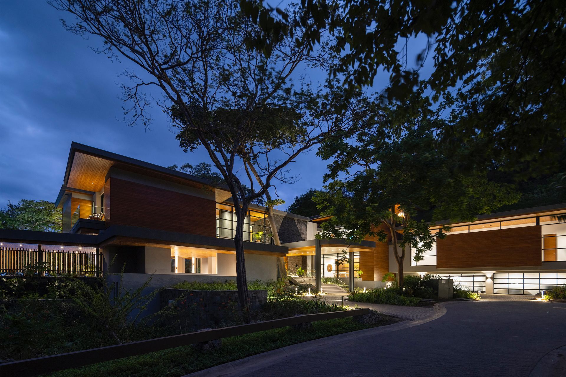 a large house is lit up at night with trees in front of it
