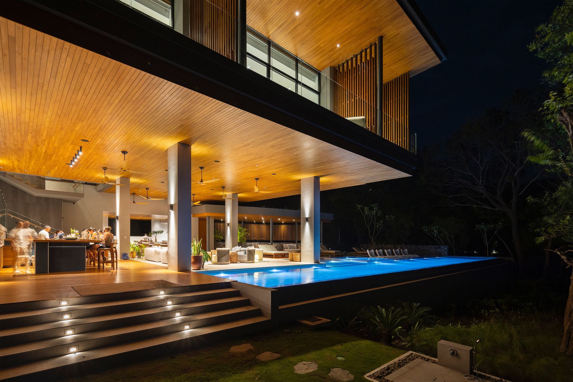 a large house with a swimming pool is lit up at night