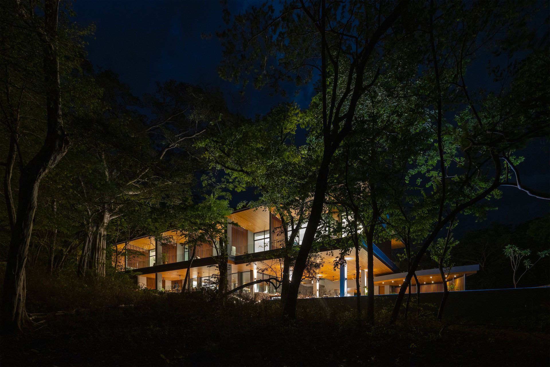 a large house is lit up at night surrounded by trees