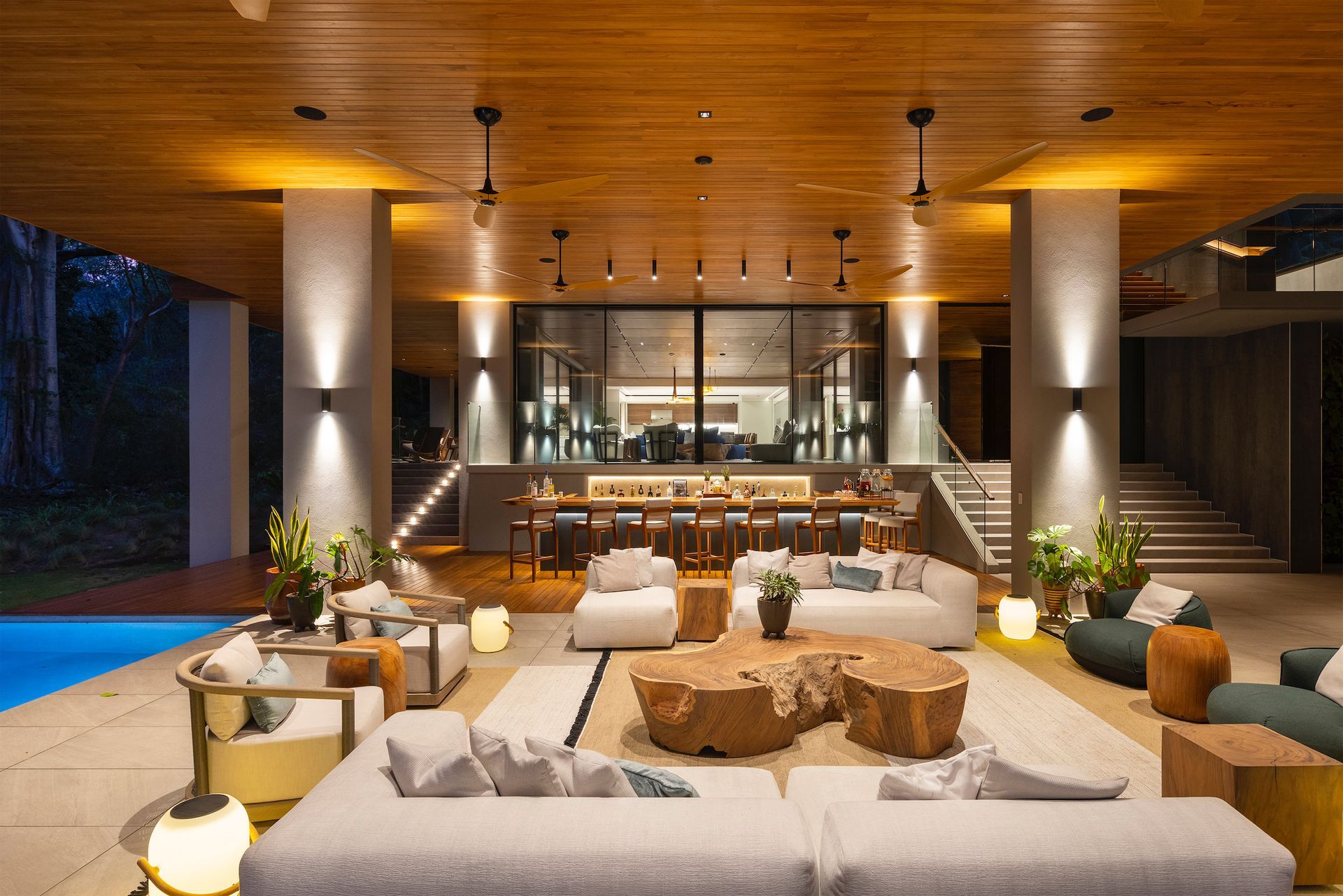 a living room with a lot of furniture and a swimming pool in the background .