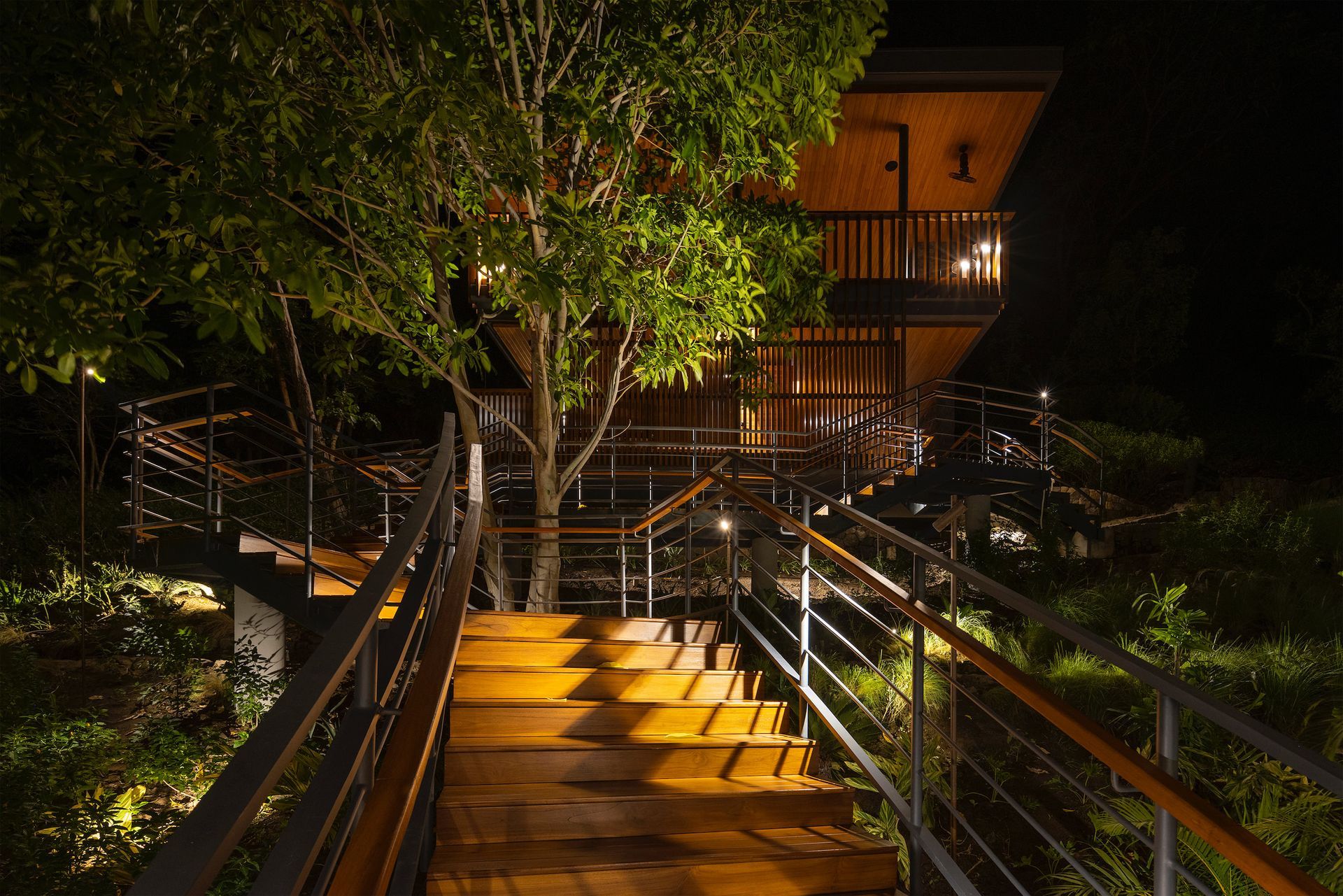 a wooden walkway leading to a house at night