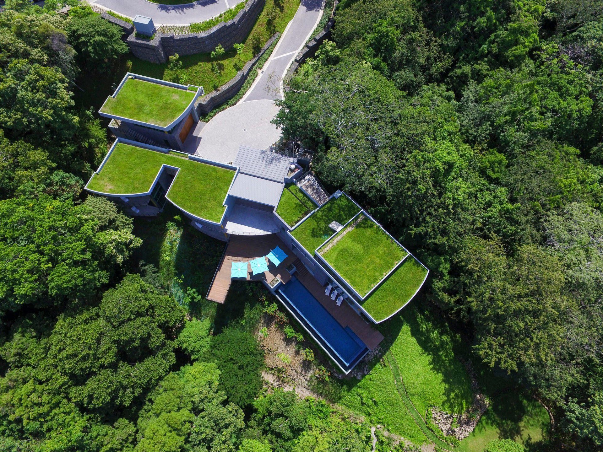 an aerial view of a house with a swimming pool surrounded by trees