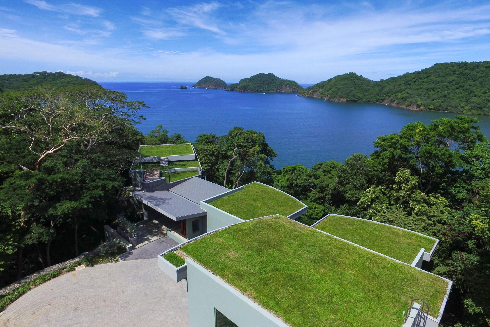 an aerial view of a house with a green roof overlooking a body of water .
