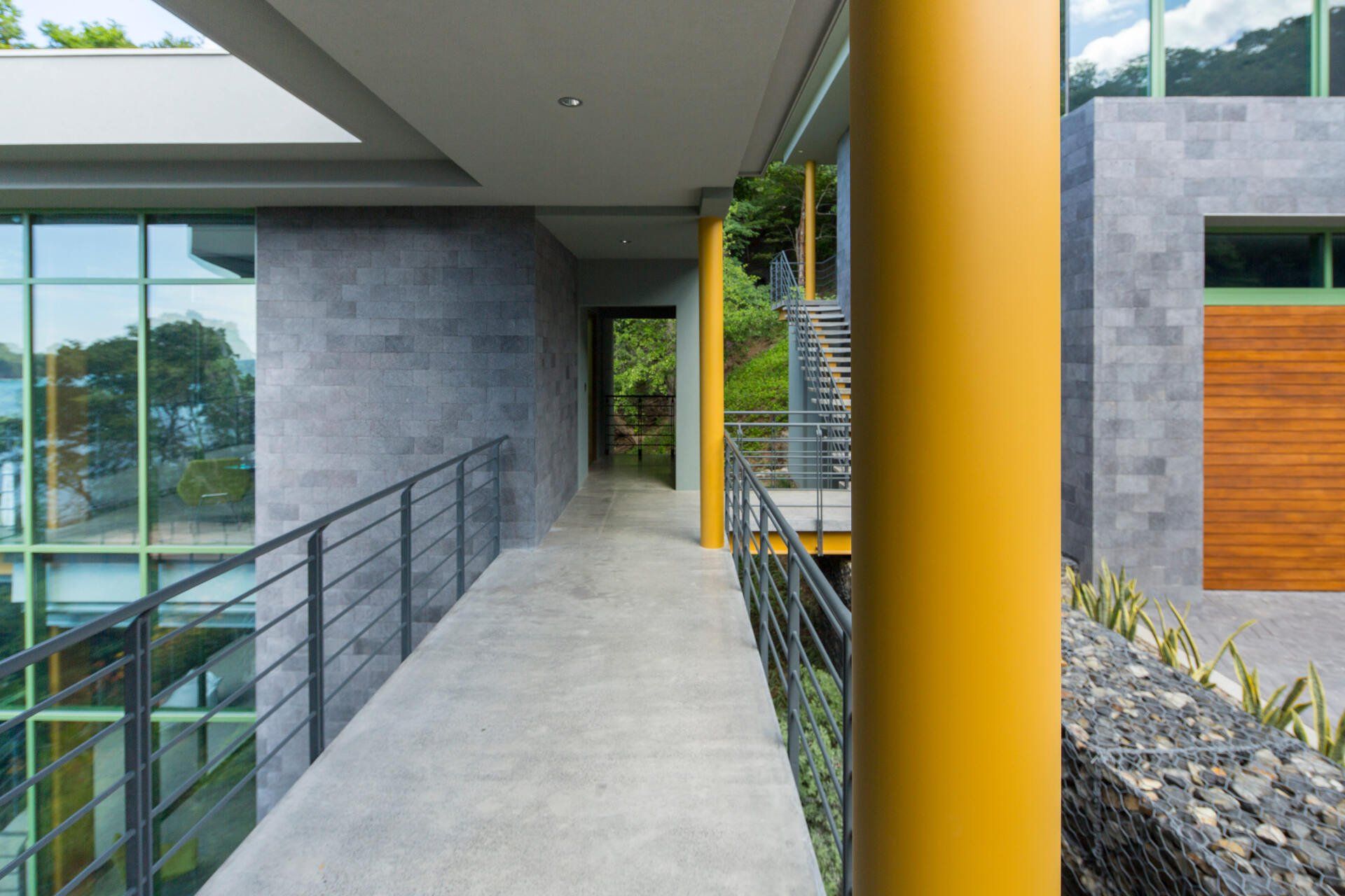 a walkway between two buildings with a yellow pole in the middle