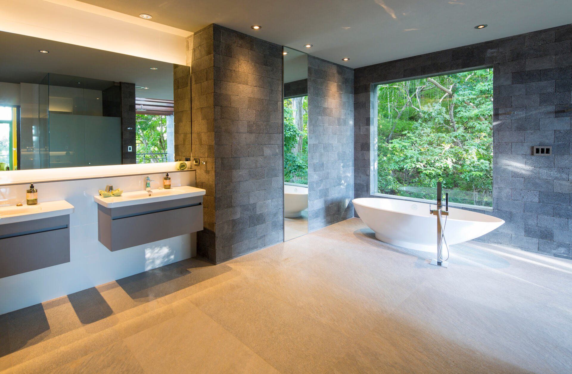 a bathroom with two sinks , a tub and a large window .