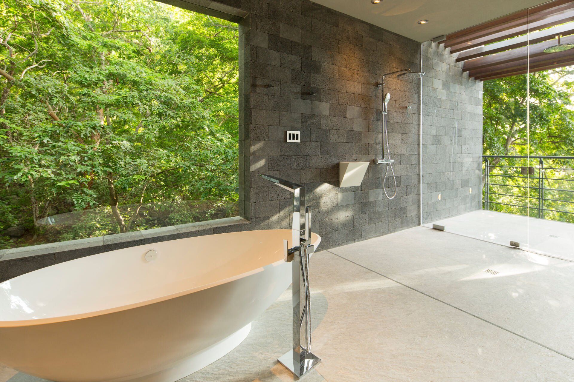 a bathroom with a bathtub and a large window with trees in the background .