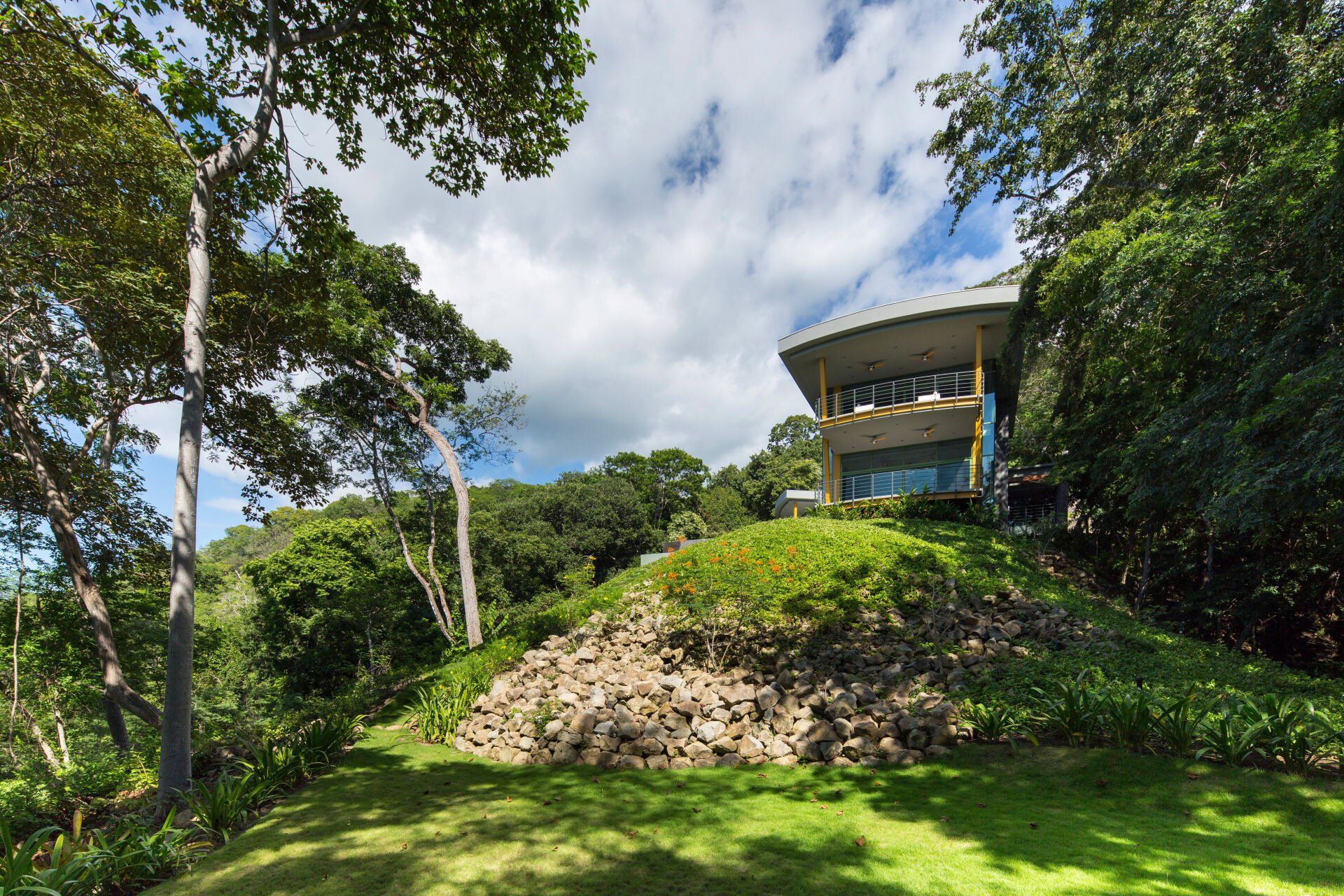 a house is sitting on top of a hill surrounded by trees .