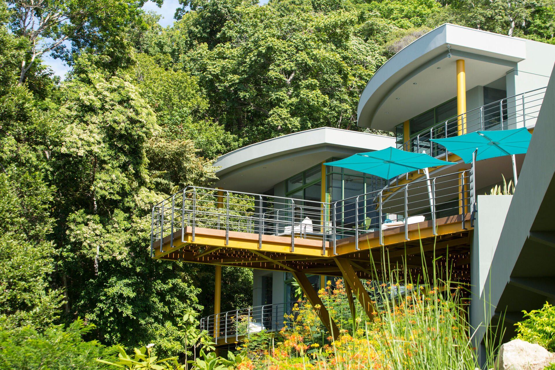 a modern house with a large deck and blue umbrellas